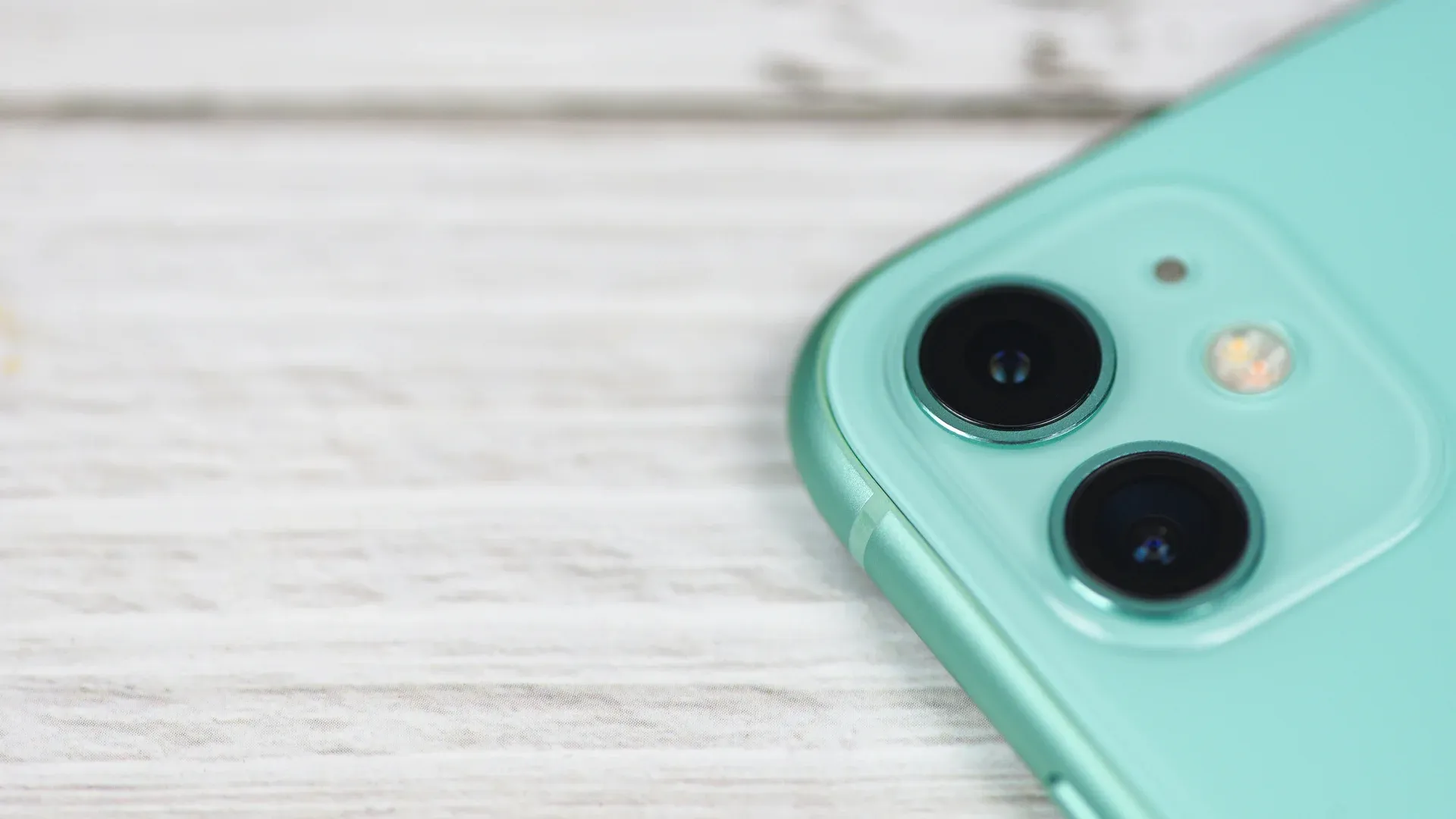 Câmera iPhone 11 azul em destaque sobre mesa de madeira