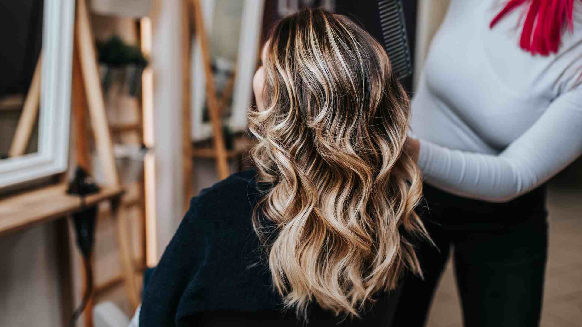 Cabeleireiro seca o cabelo com secador de cabelo para uma mulher após um  corte de cabelo no salão