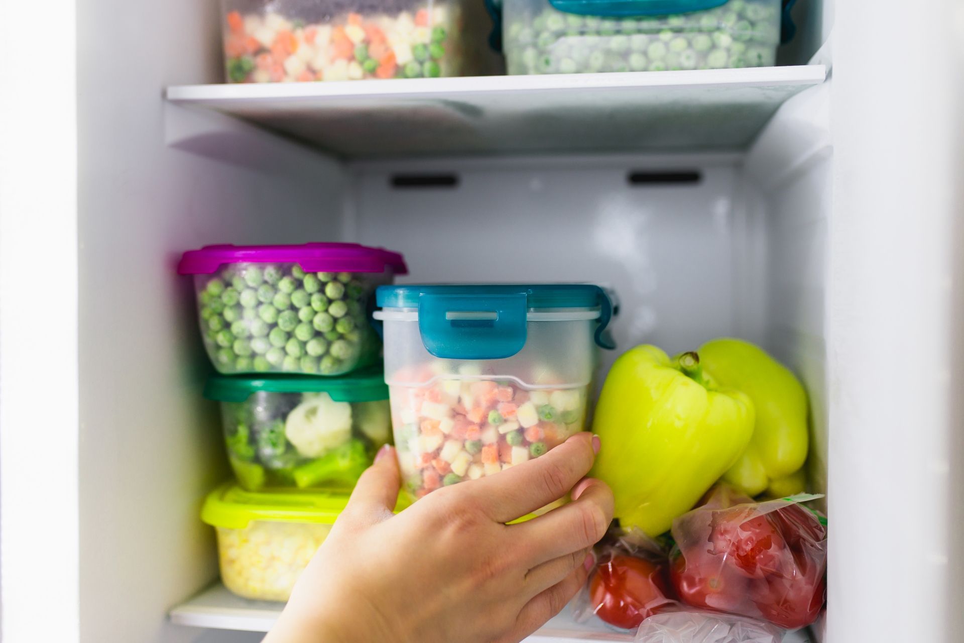 Pessoa colocando potes e alimentos dentro de um freezer
