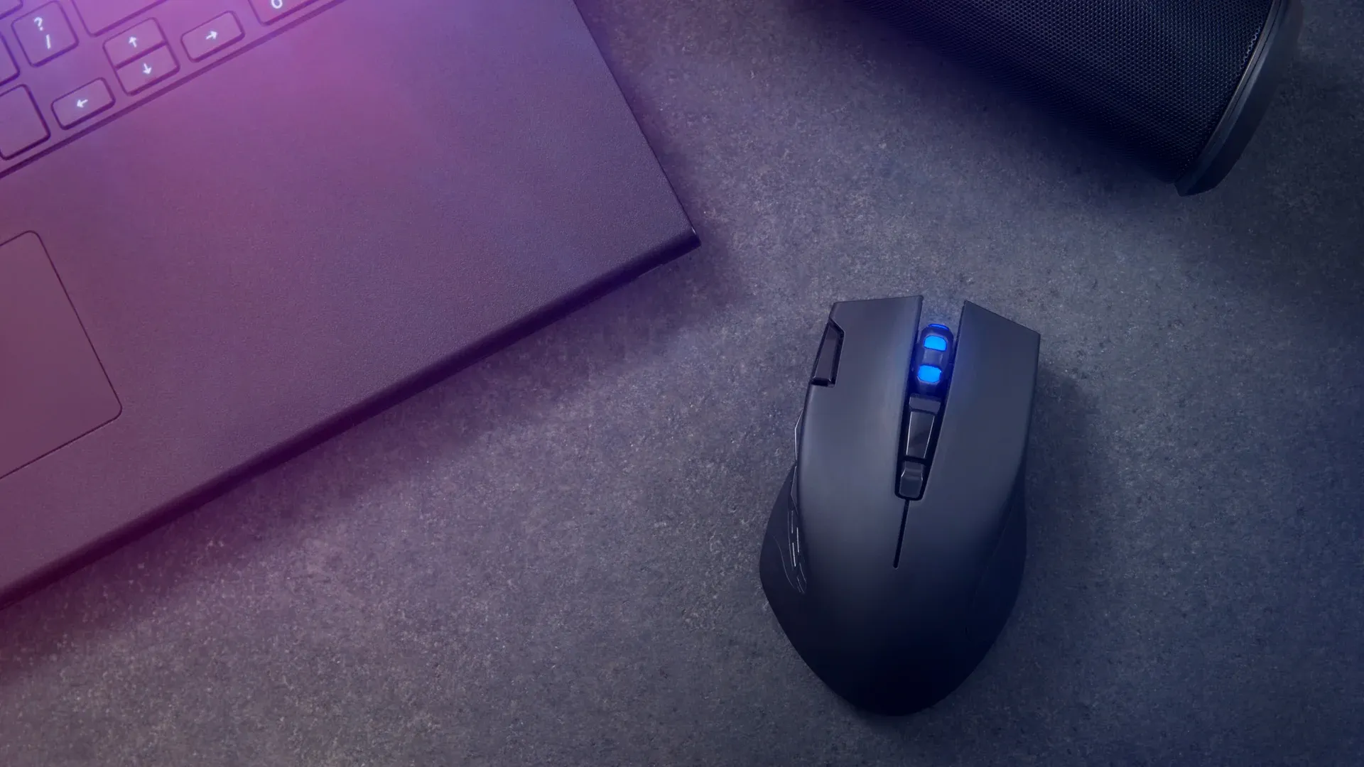 Mouse sem fio com luz azul e design gamer sobre uma mesa com um notebook ao lado