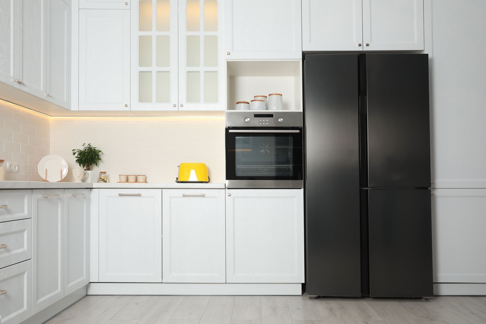 Cozinha com móveis planejados brancos e uma geladeira side by side preta em destaque