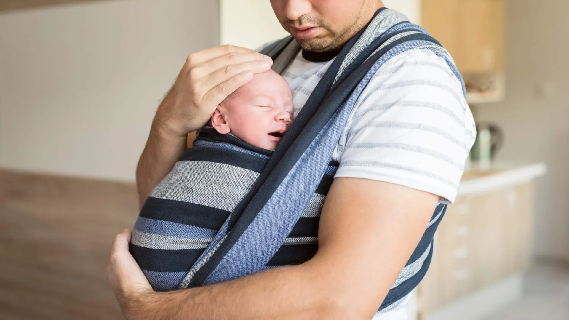 Pai de primeira viagem segura bebê amarrado em um sling
