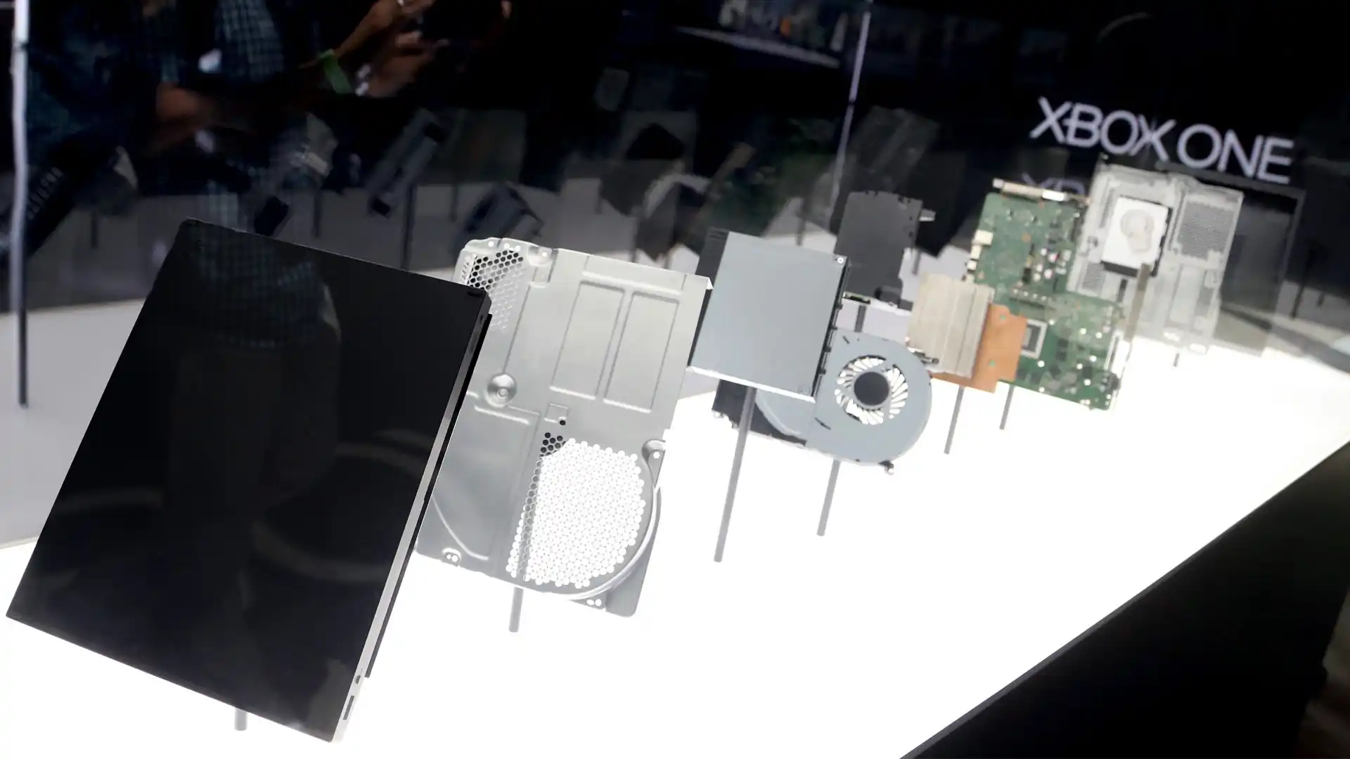 Foto com várias placas do Xbox One separadas de maneira afastada dentro de uma caixa de vidro na revelação do console