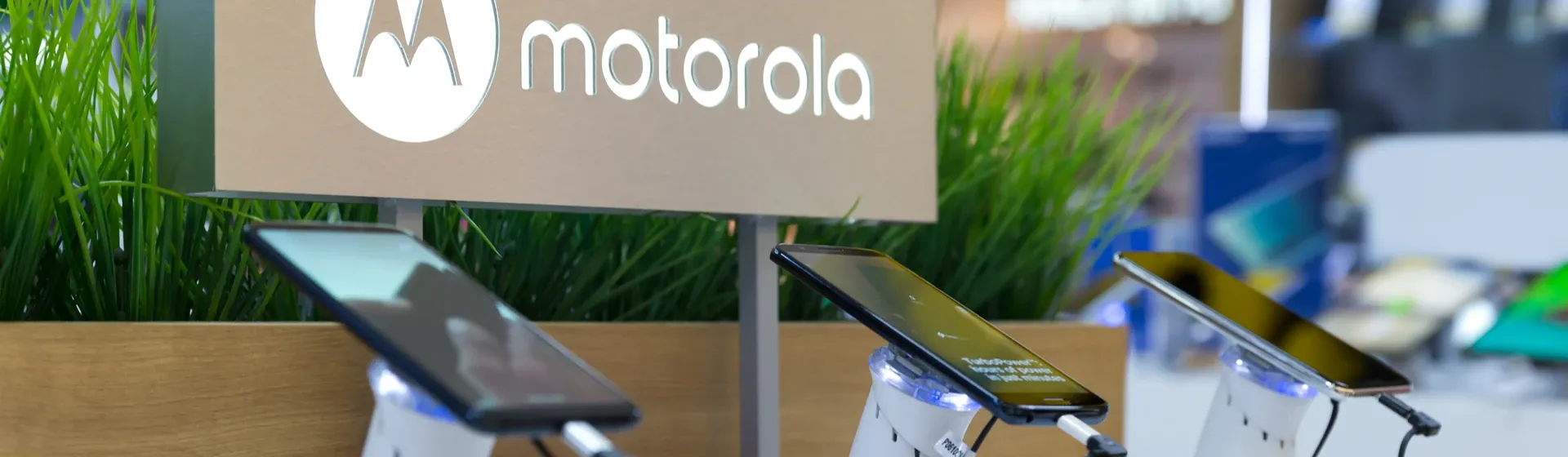 Mesa com três modelos de celular Motorola em uma loja