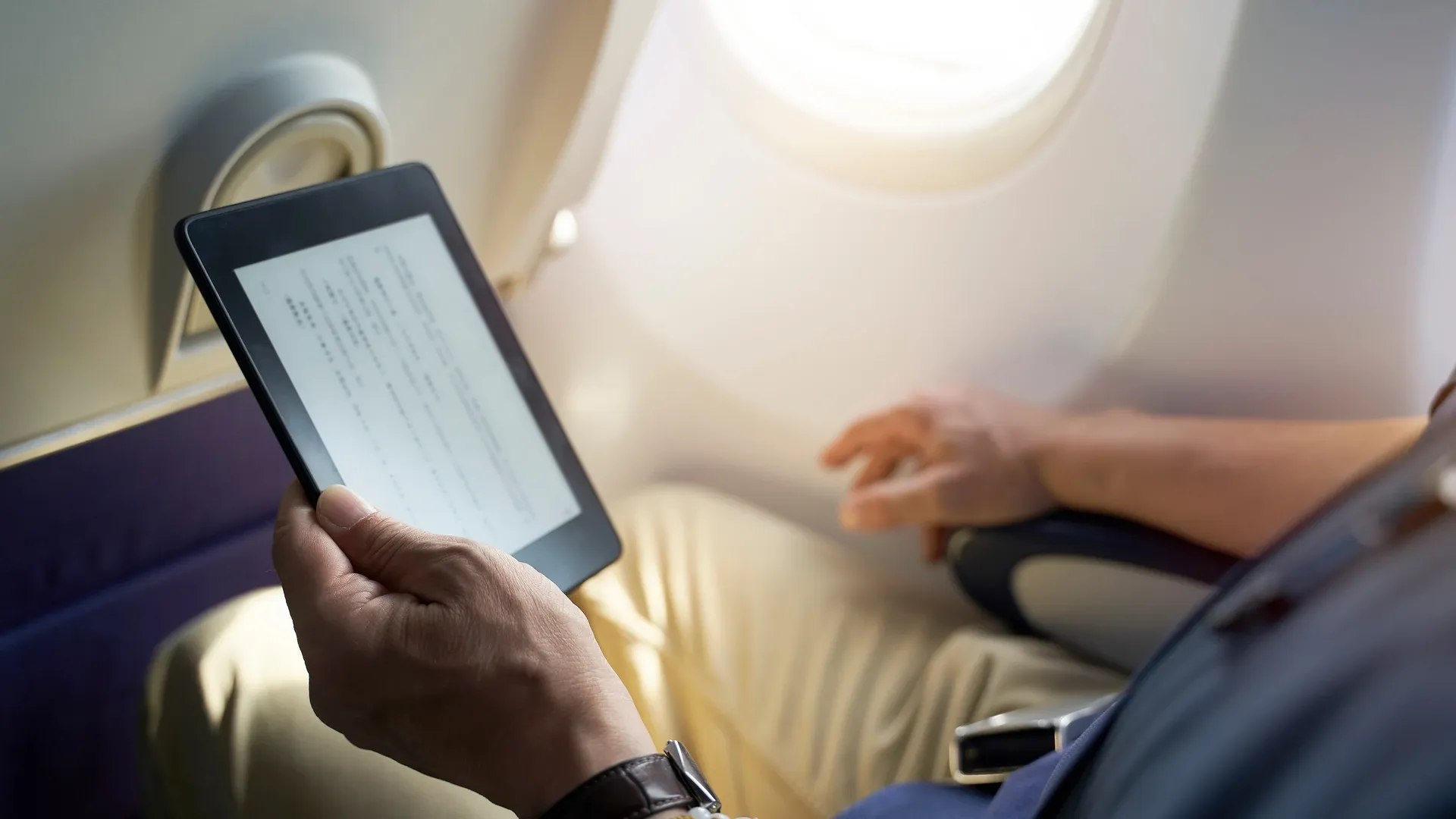 Homem em avião segura o seu Kindle Oasis 2021 em avião