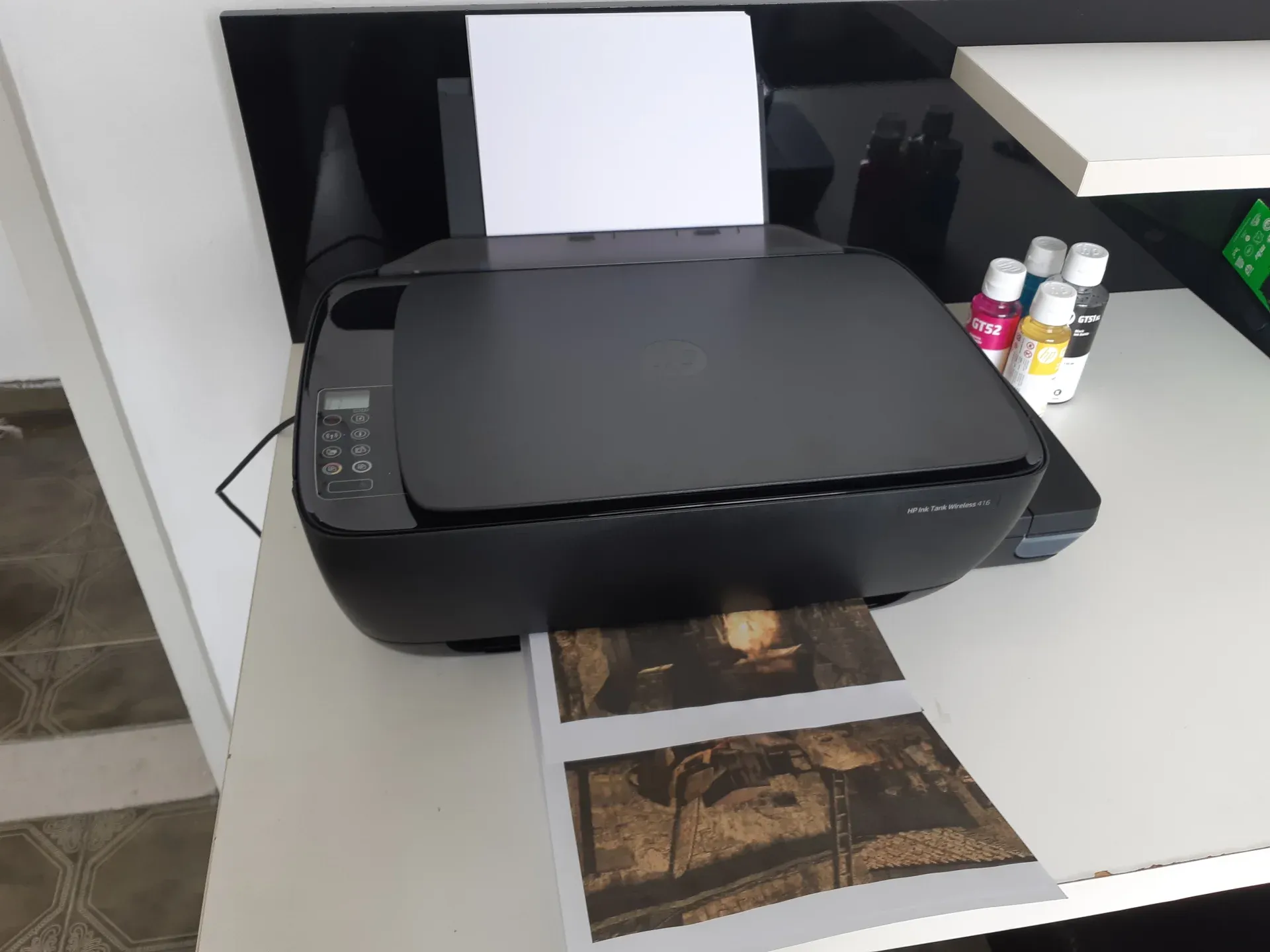 Impressora HP 416 sobre mesa branca imprimindo imagem colorida