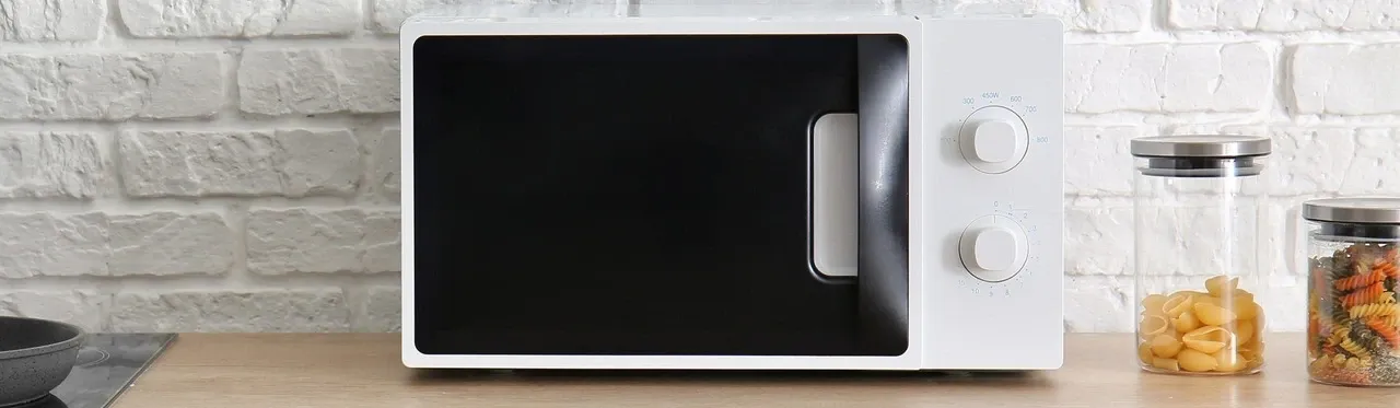 Micro-ondas 20 litros branco com a porta preta sobre bancada de cozinha marrom clara 