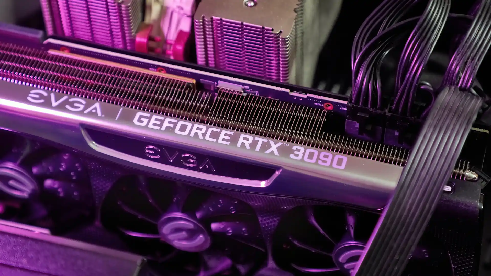 Detalhe da placa "EVGA GeForce RTX 3090" dentro de um computador com uma luz roxa.