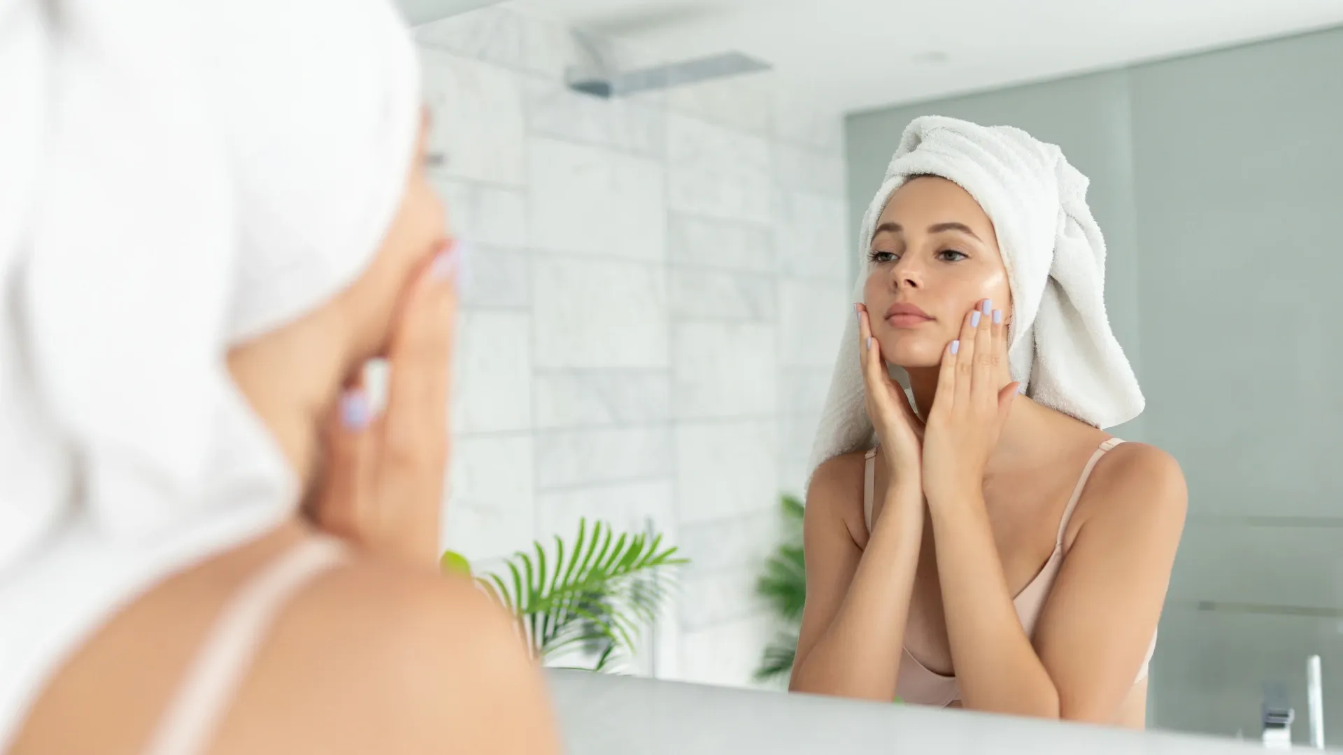 Mulher caucasiana limpando sua pele em frente ao espelho