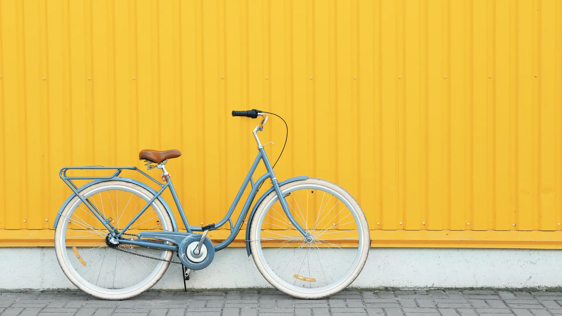 Bicicleta retrô azul encostada em parede amarela