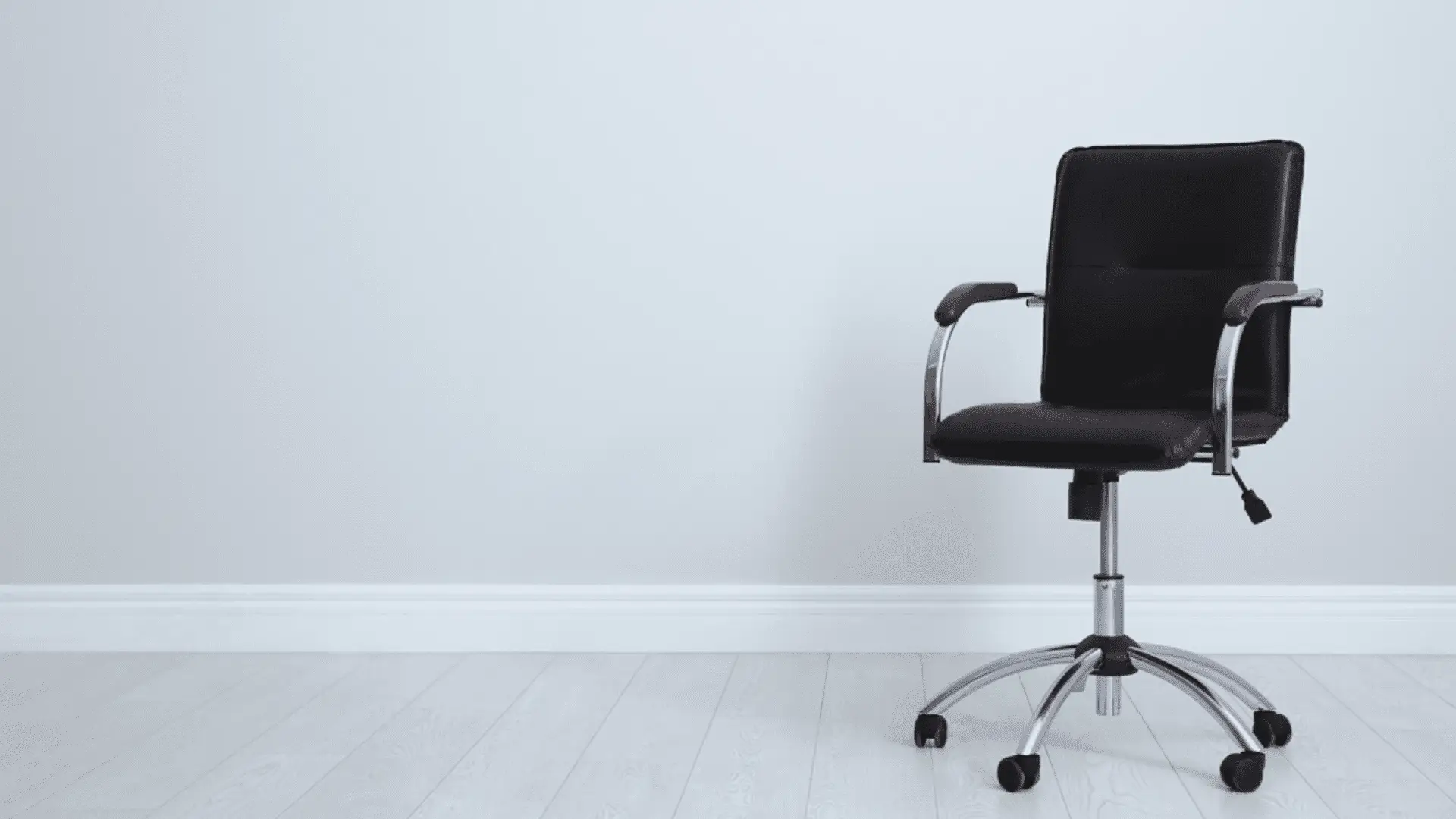Cadeira de escritório preta em fundo com parede branca