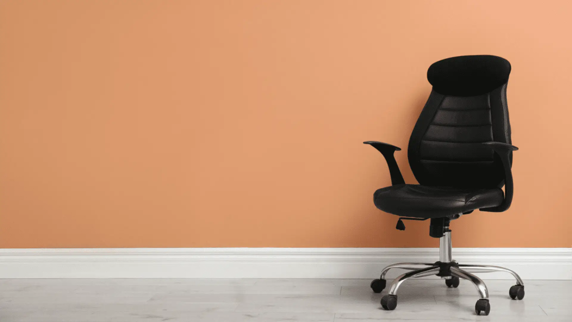 Cadeira de escritório preta em fundo com parede laranja