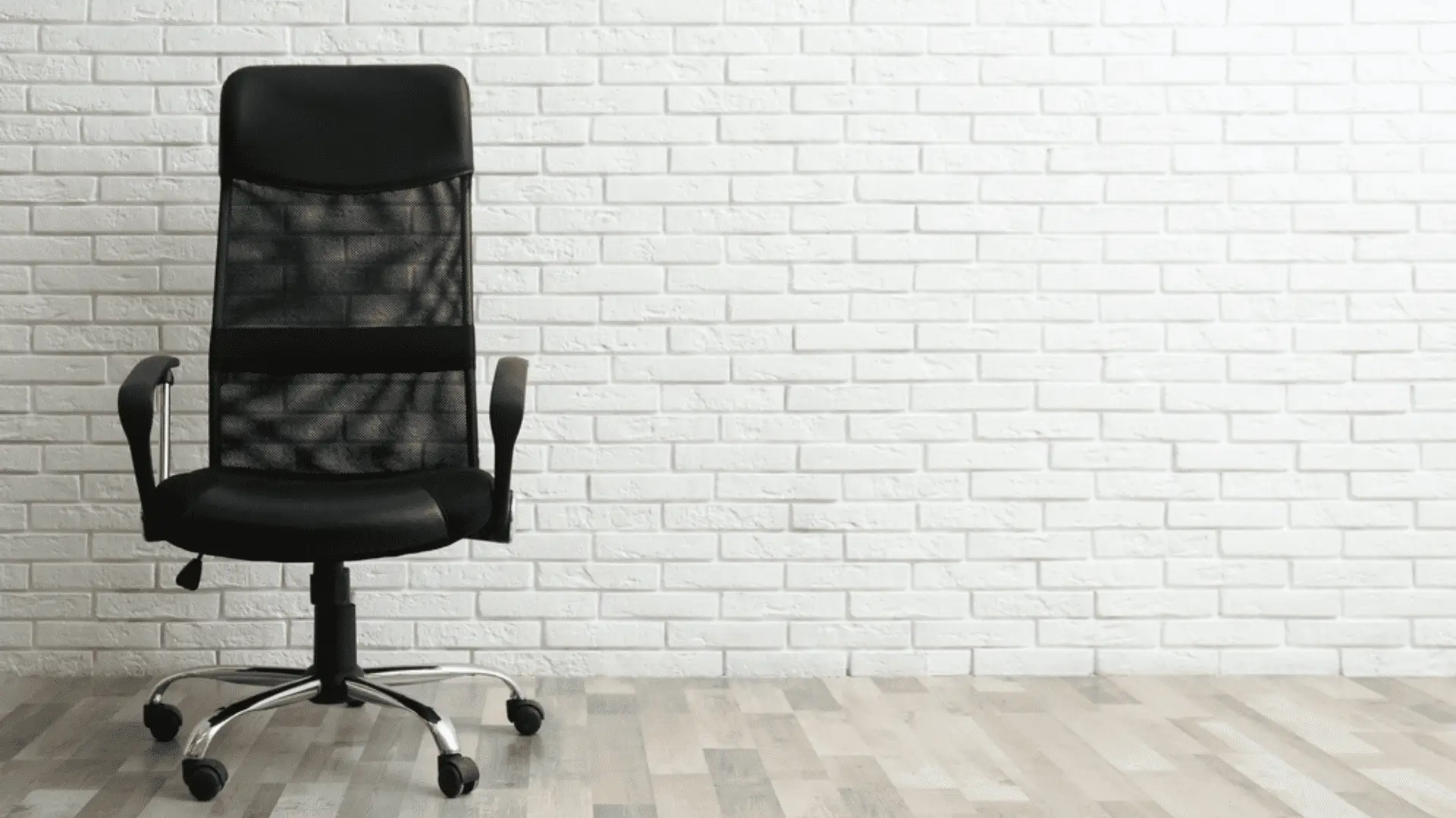 Cadeira de escritório preto em fundo de parede de tijolos brancos