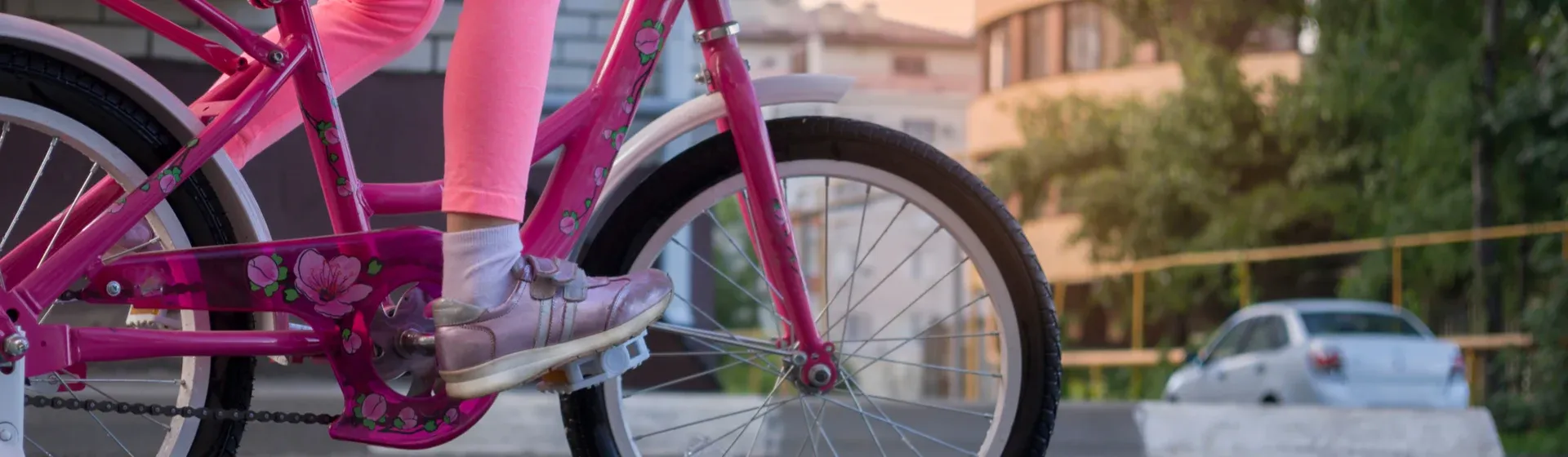 Criança pedalando em uma bicicleta rosa infantil na rua