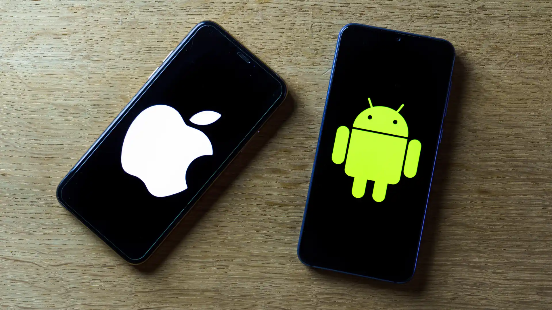Foto de Android ao lado de iPhone sobre uma mesa de madeira