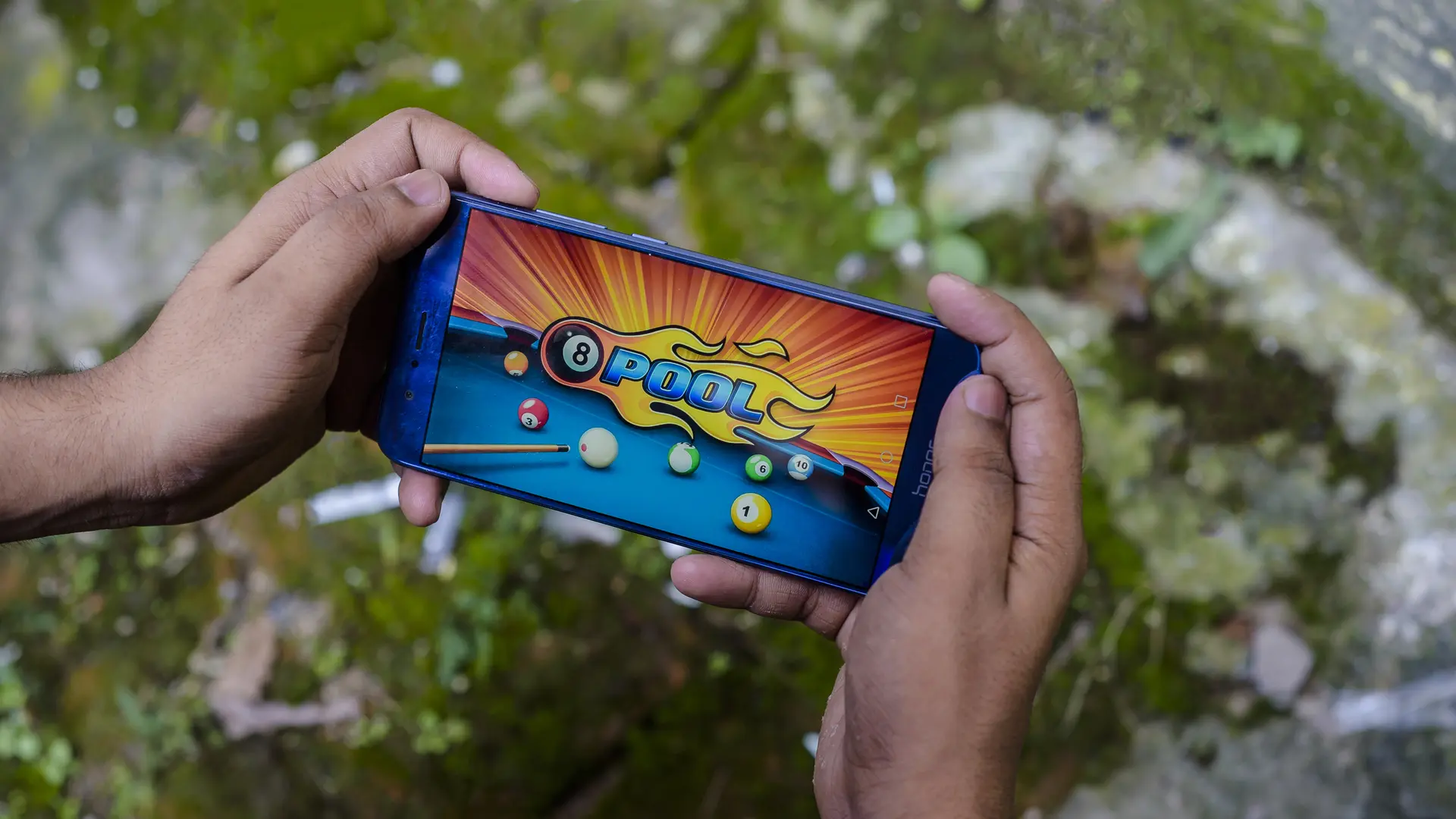 Mãos com jogo para celular 8 Ball Pool na tela