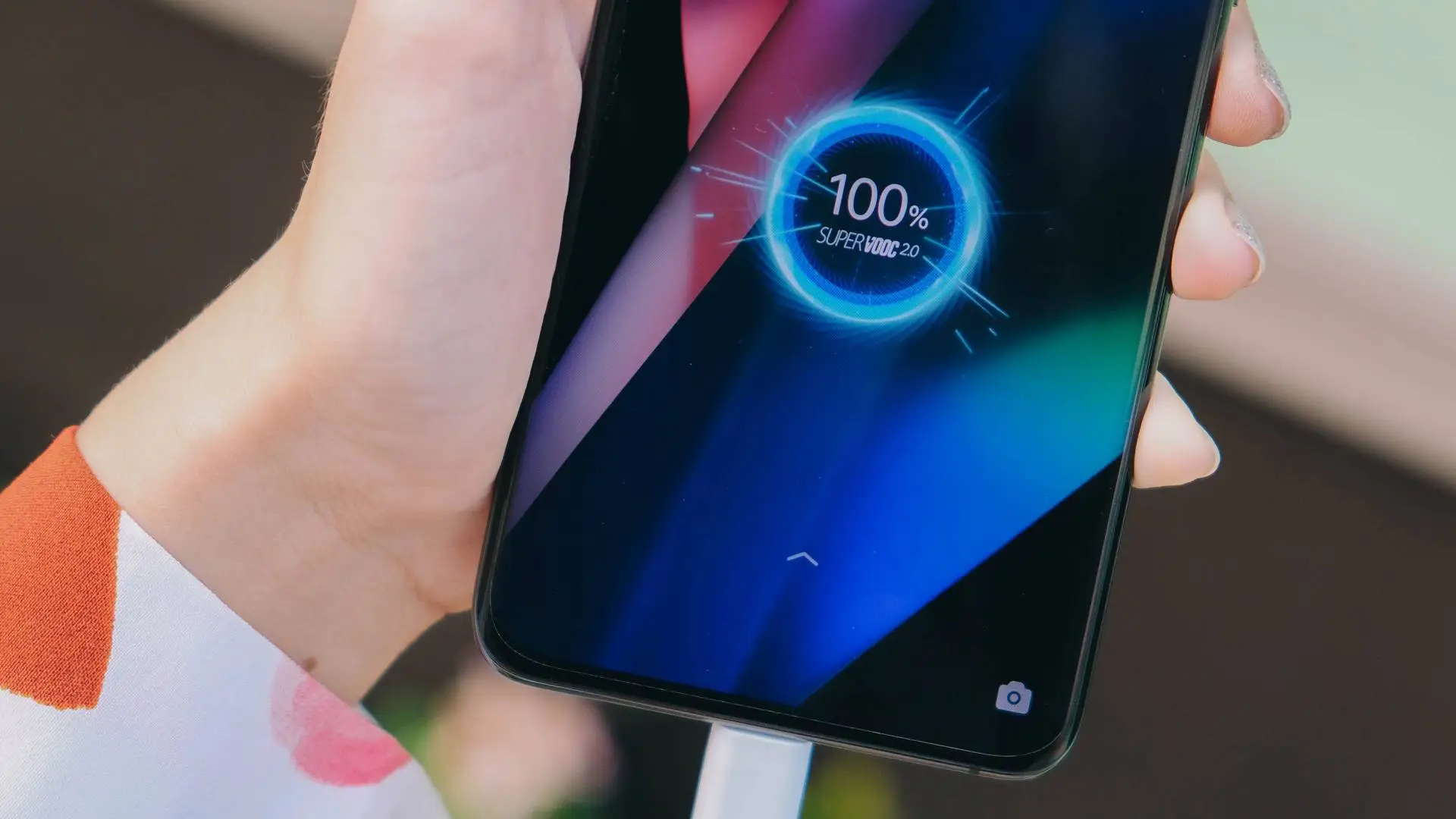 Mão de mulher segura o seu Galaxy A72 conectado ao carregador com 100% de bateria