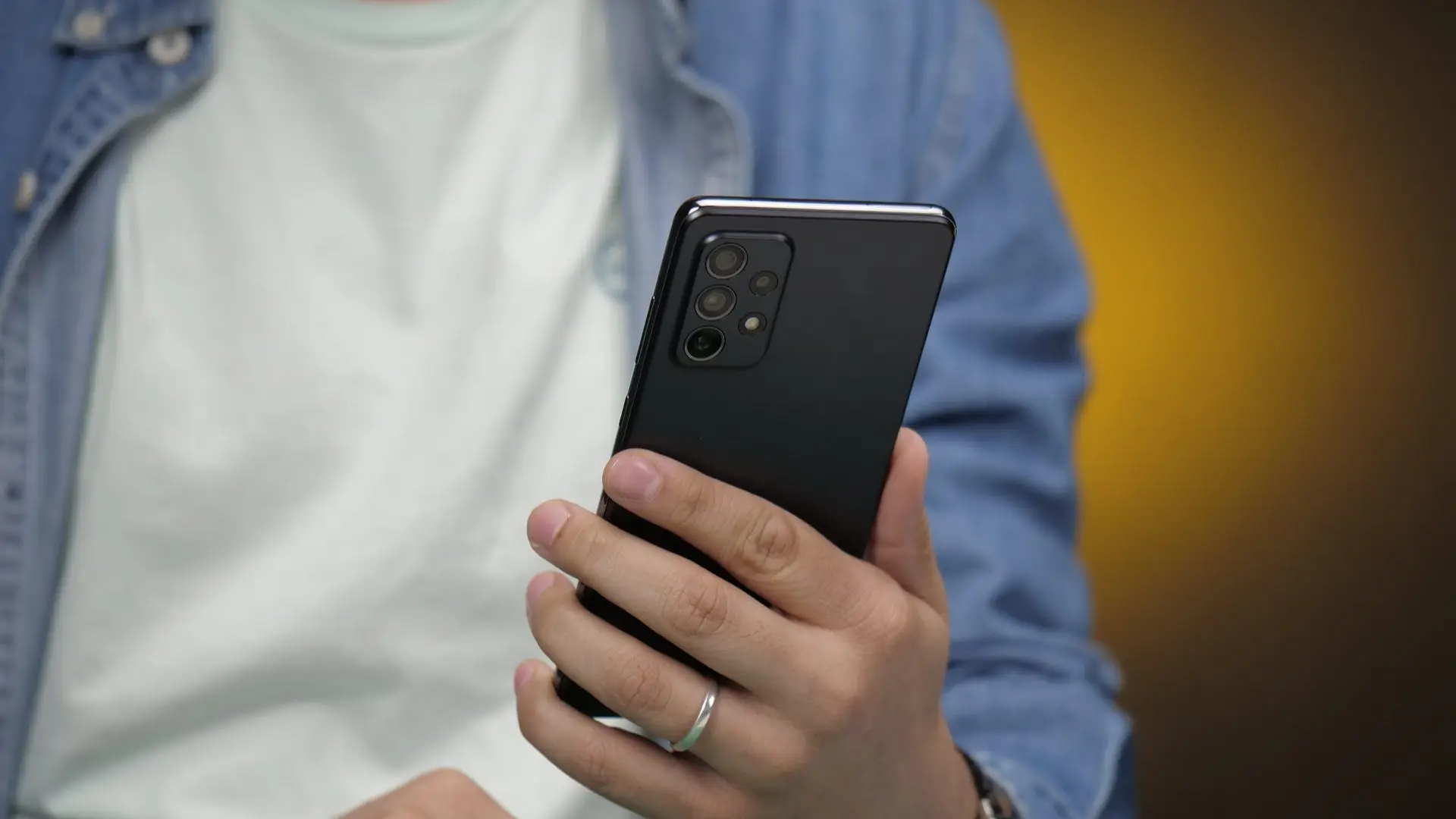 Mulher de camisa branca e casaco jeans segura seu Galaxy A72