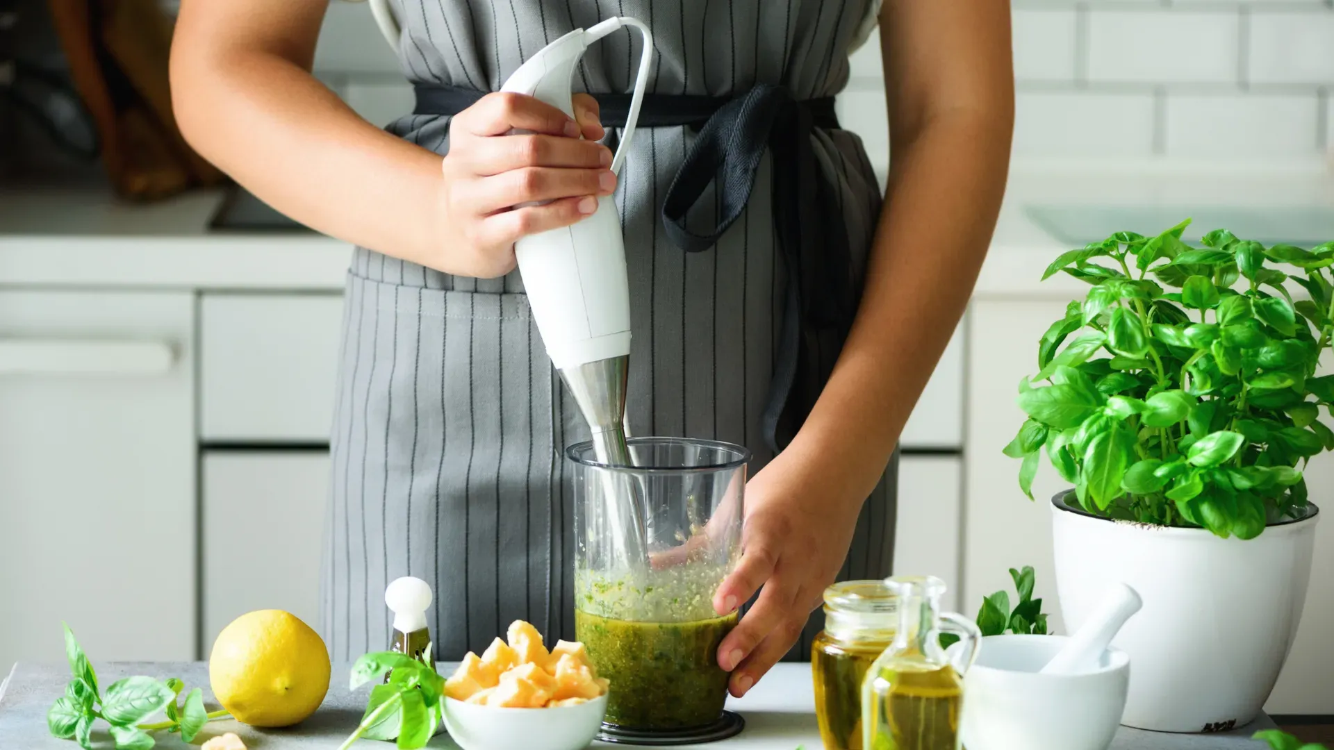 Mulher usando mixer para fazer suco verde em cozinha