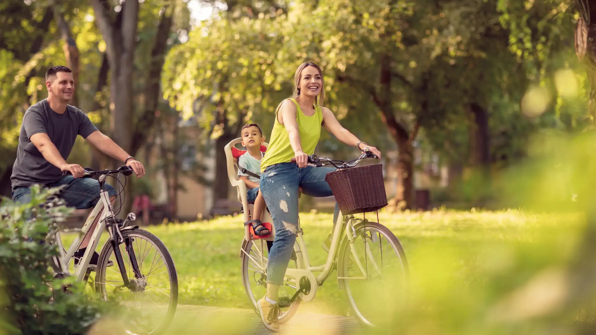 pai e mãe andam de bicicleta com criança na cadeirinha traseira