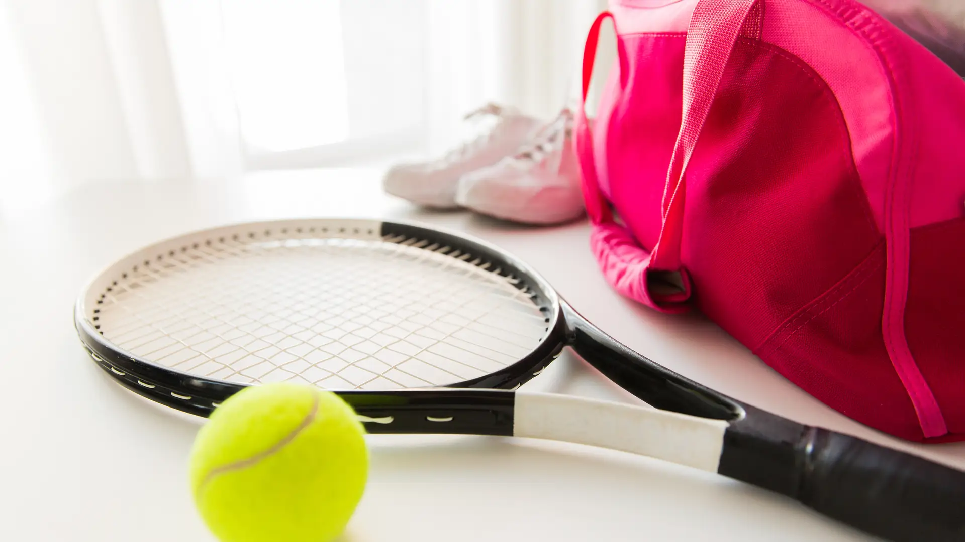 Close em raquete de tênis, bolas e raqueteira rosa