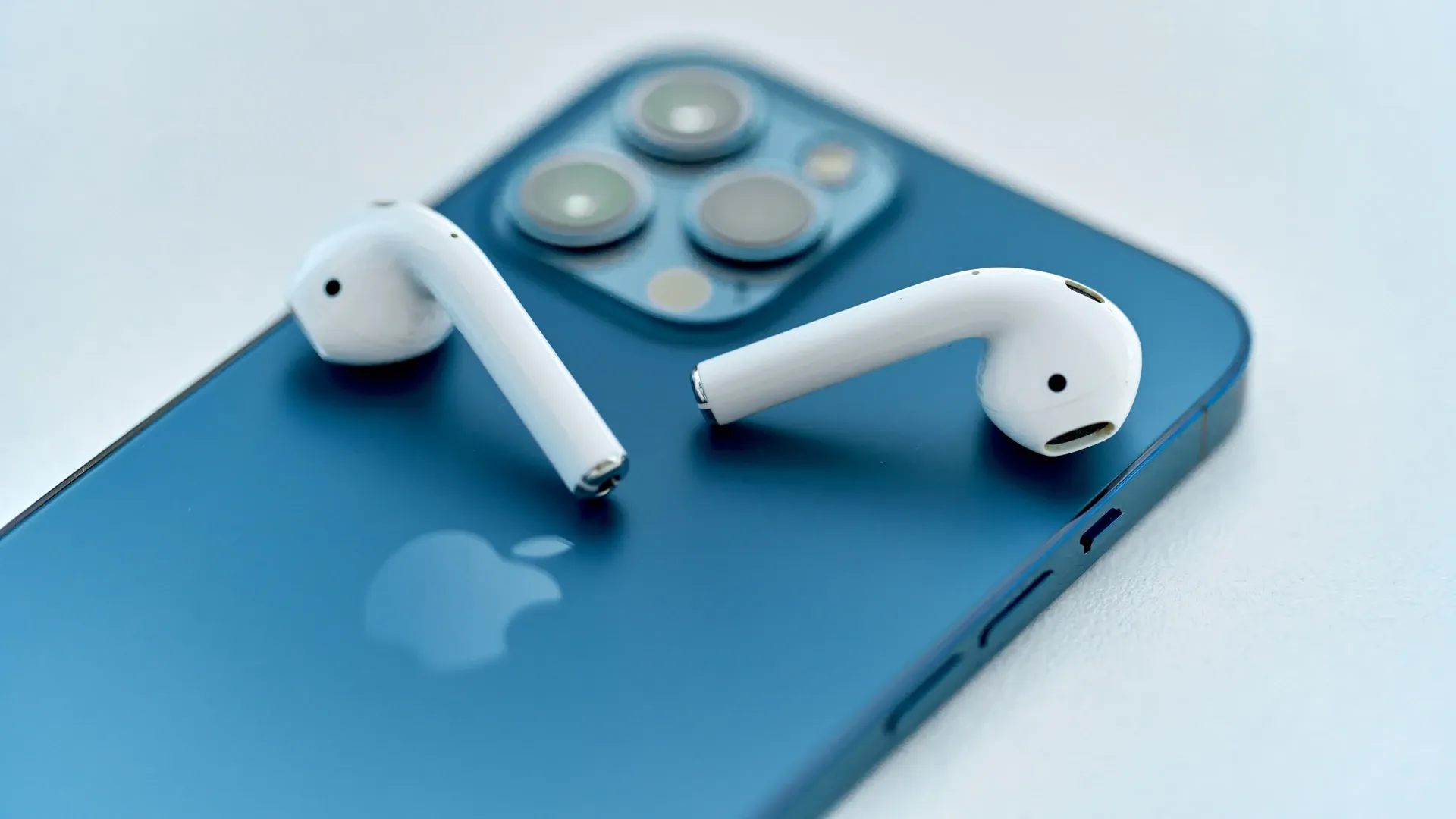 Fone Apple AirPods 2 sobre iPhone azul em fundo cinza