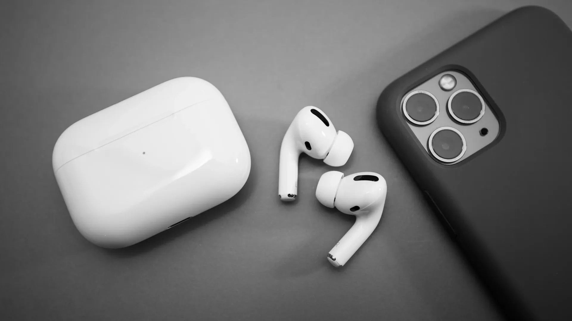 Fone intra-auricular AirPods Pro ao lado do seu estojo e de um iPhone