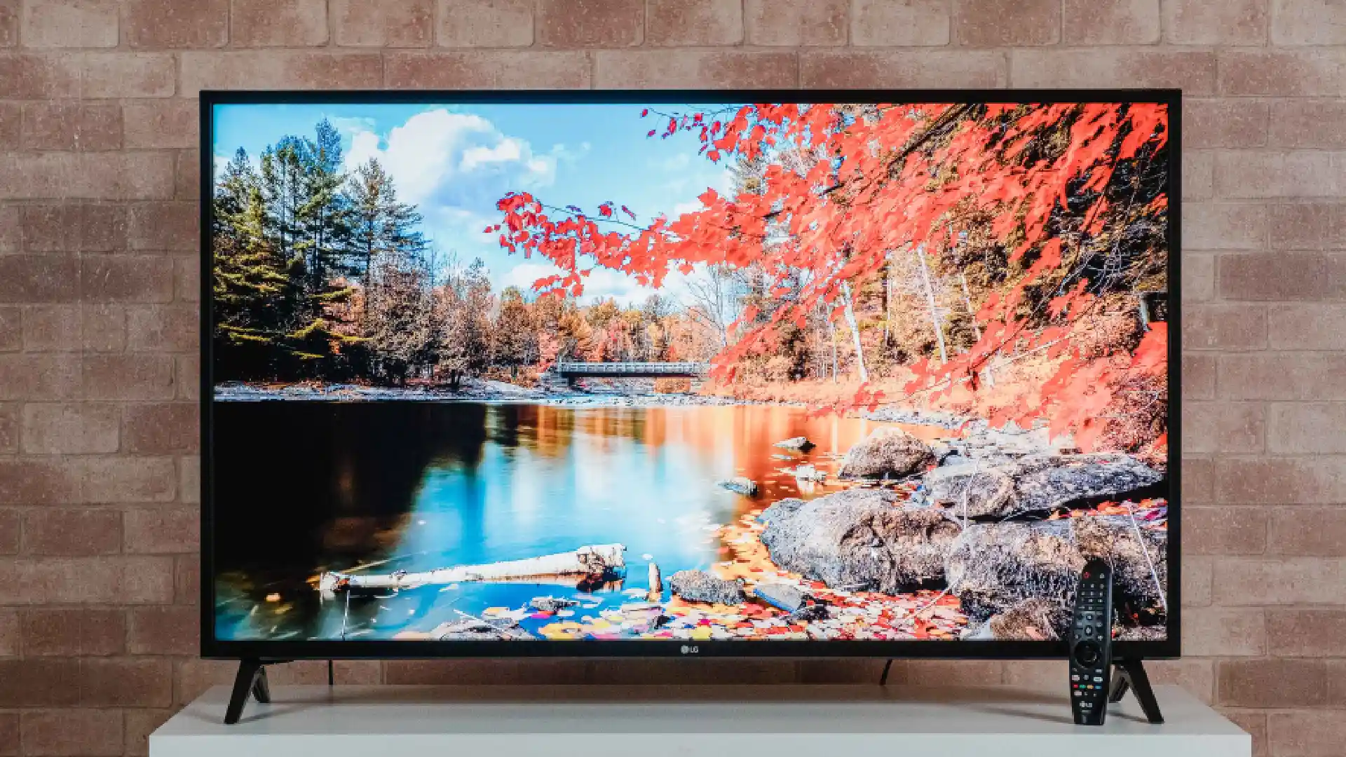 TV LG UN7310 sobre rack branco exibindo imagem de paisagem natural na tela