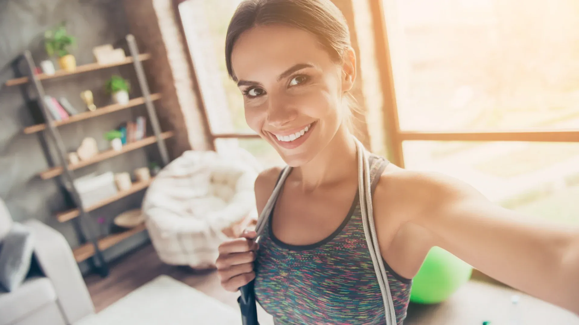 Mulher segurando câmera em pose de selfie vestida com roupas de academia em casa
