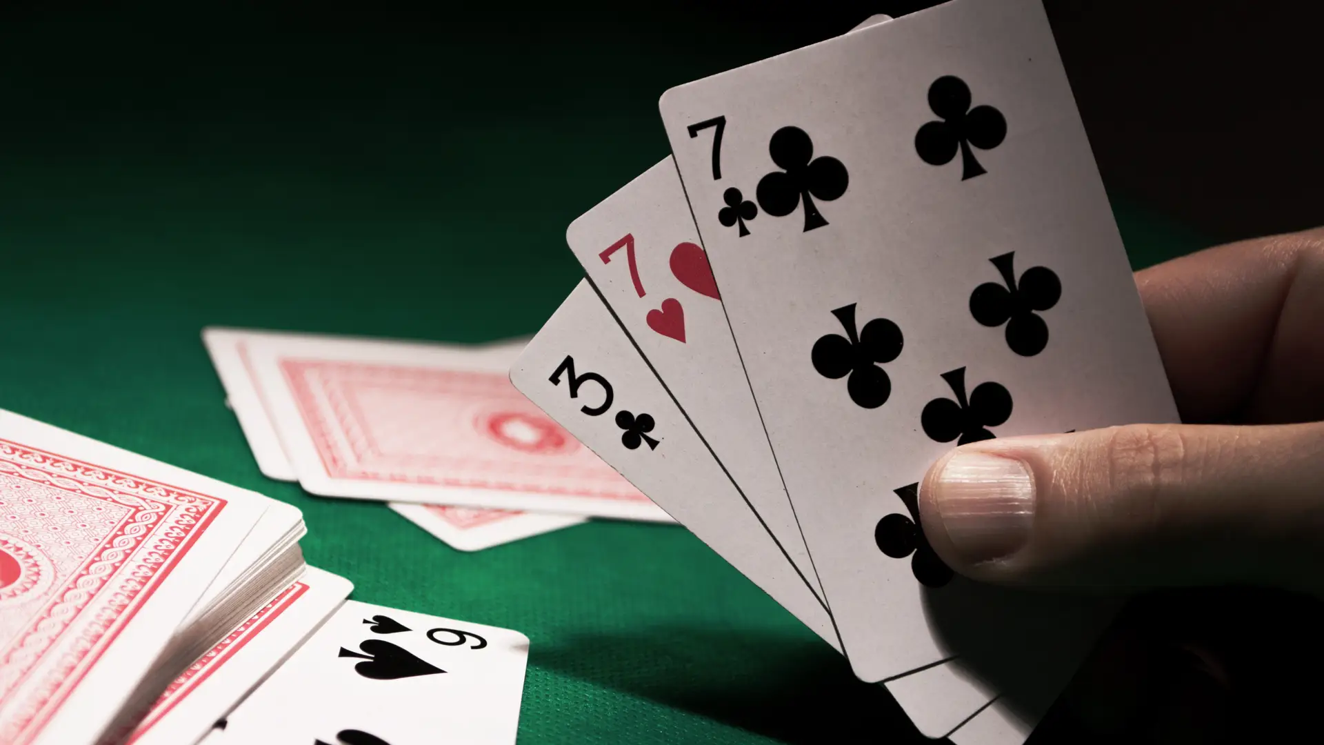 Mesa com jogos com baralho com pessoa segurando três cartas