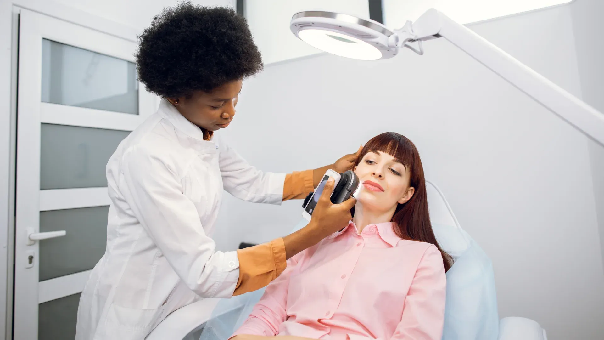 Dermatologista examina pele da paciente com um aparelho