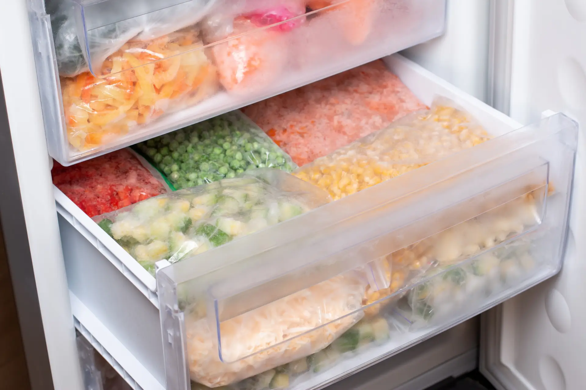 Freezer aberto com alimentos organizados em sacos plásticos nas gavetas