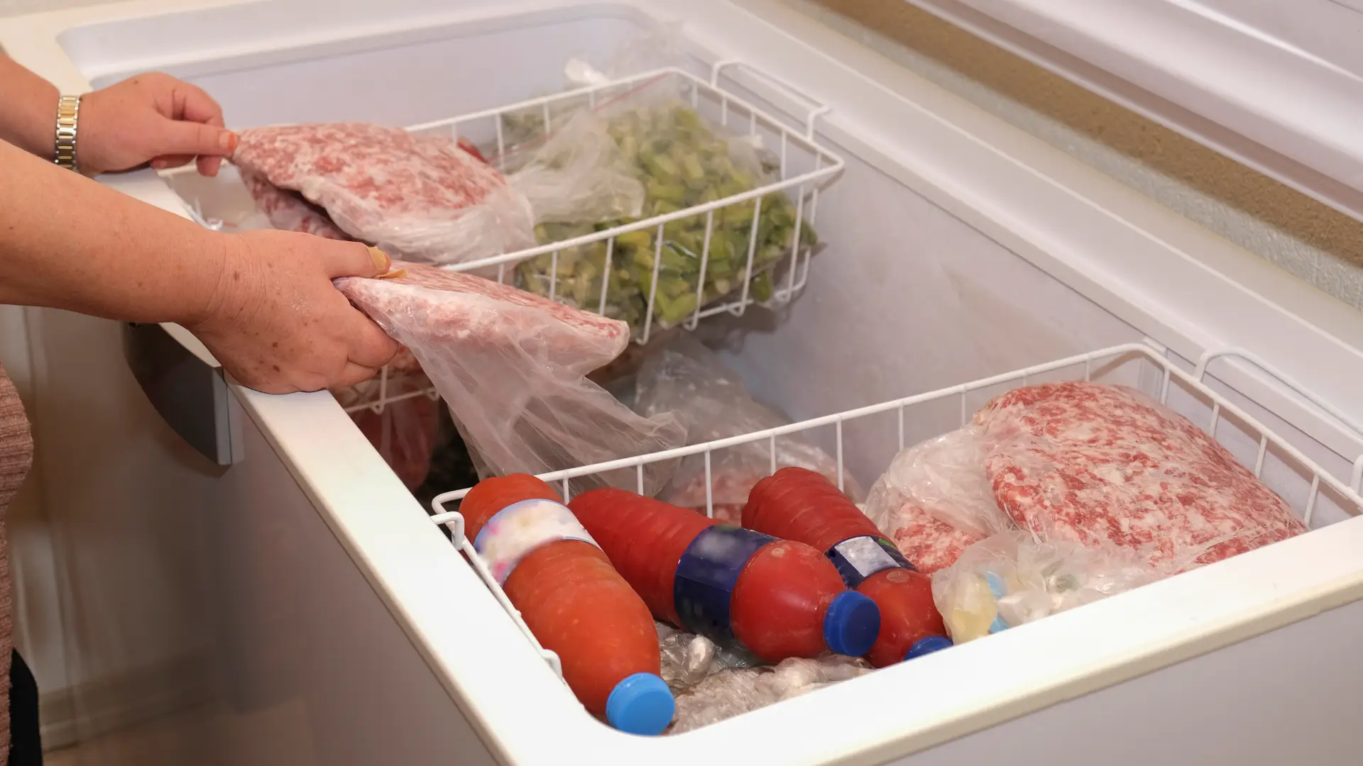 Mulher mexendo em alimentos estocados em um freezer horizontal