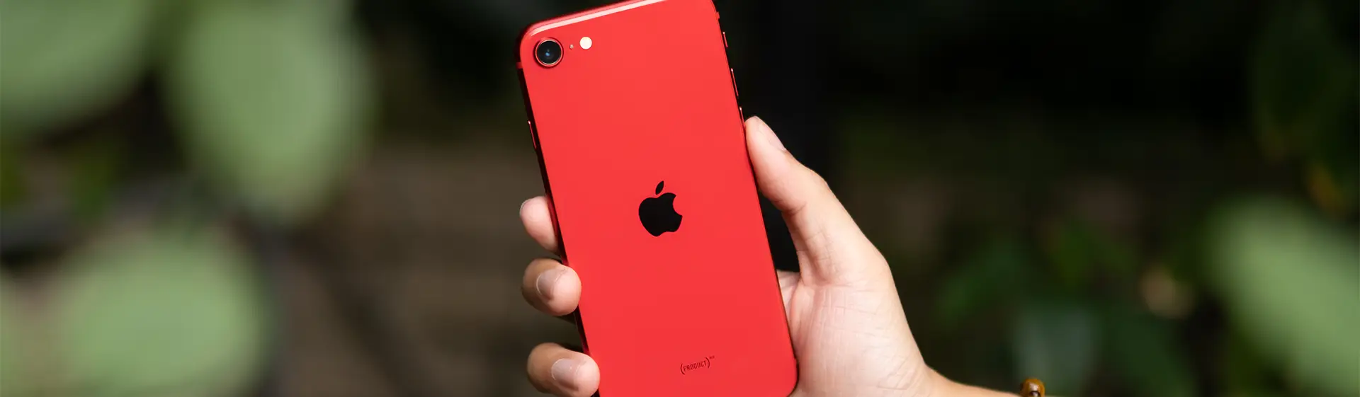 iPhone barato na cor vermelha na mão de pessoa com fundo desfocado