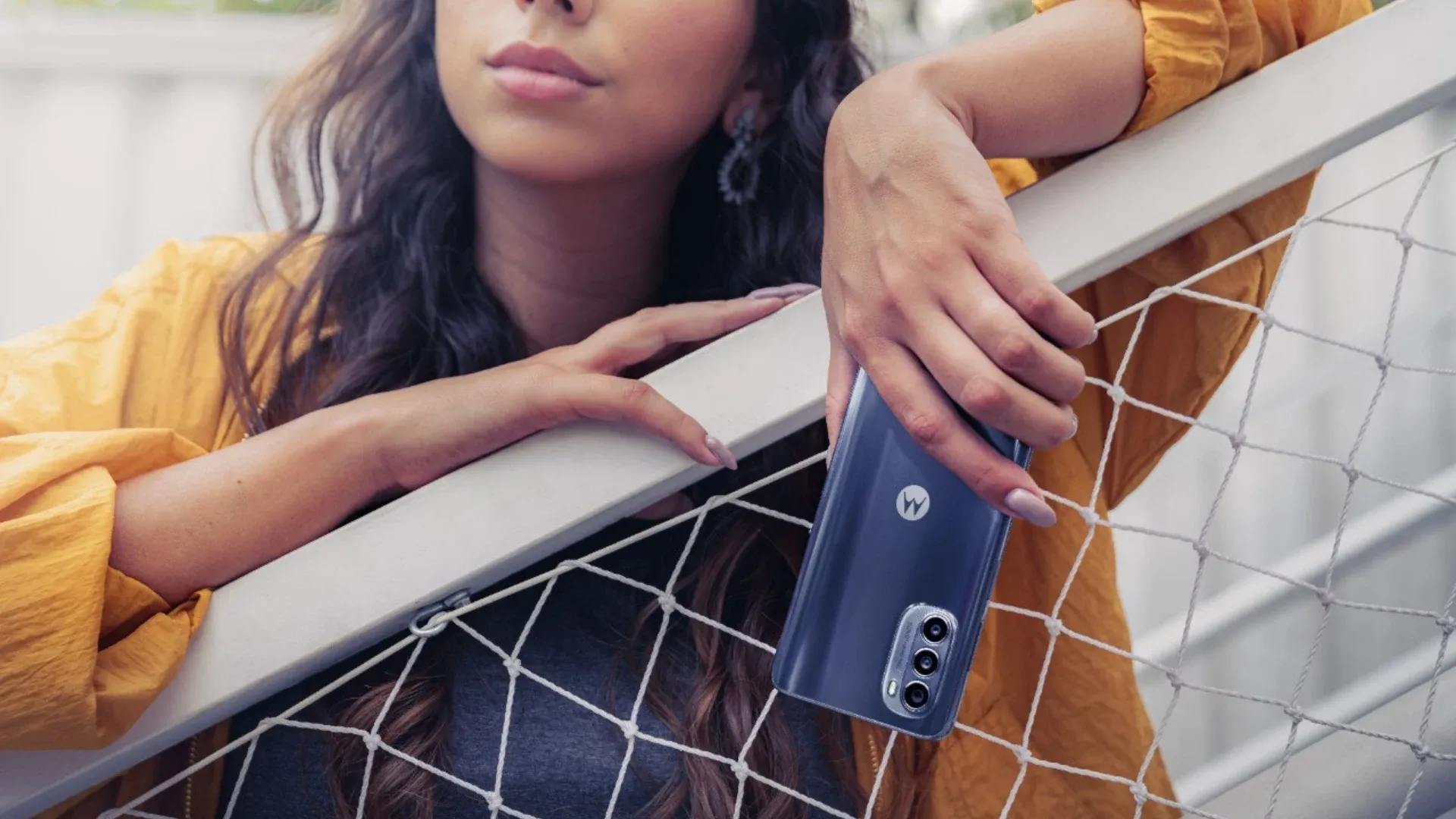 mulher na grade segurando moto g52