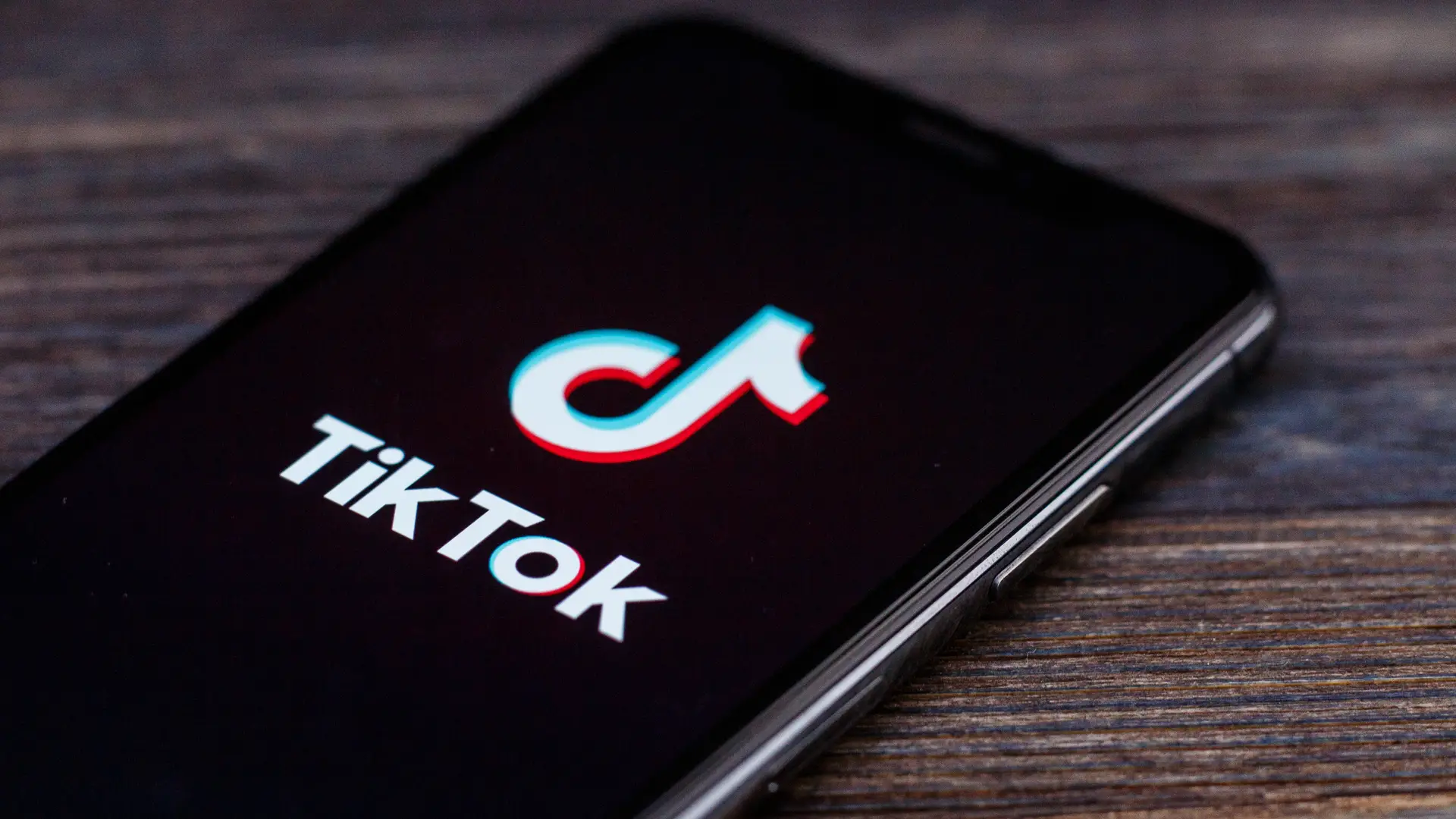 Celular com TikTok aberto sobre mesa de madeira