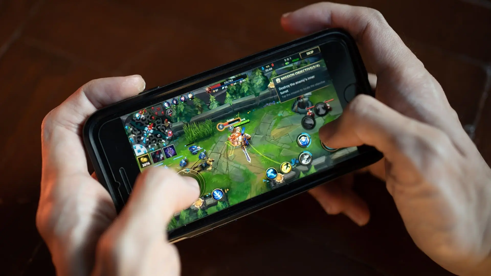 O jogo online Wild Rift é jogado por uma pessoa, que segura com as duas mãos um celular da cor preta