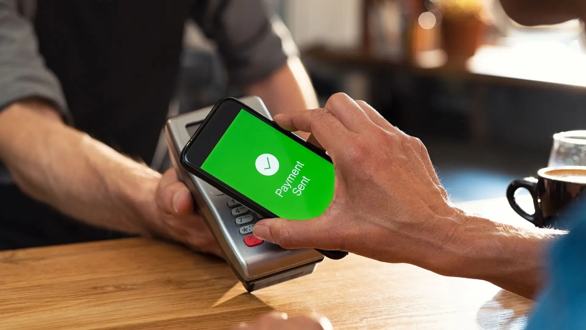 Homem faz pagamento usando NFC no celular em máquina de cartão