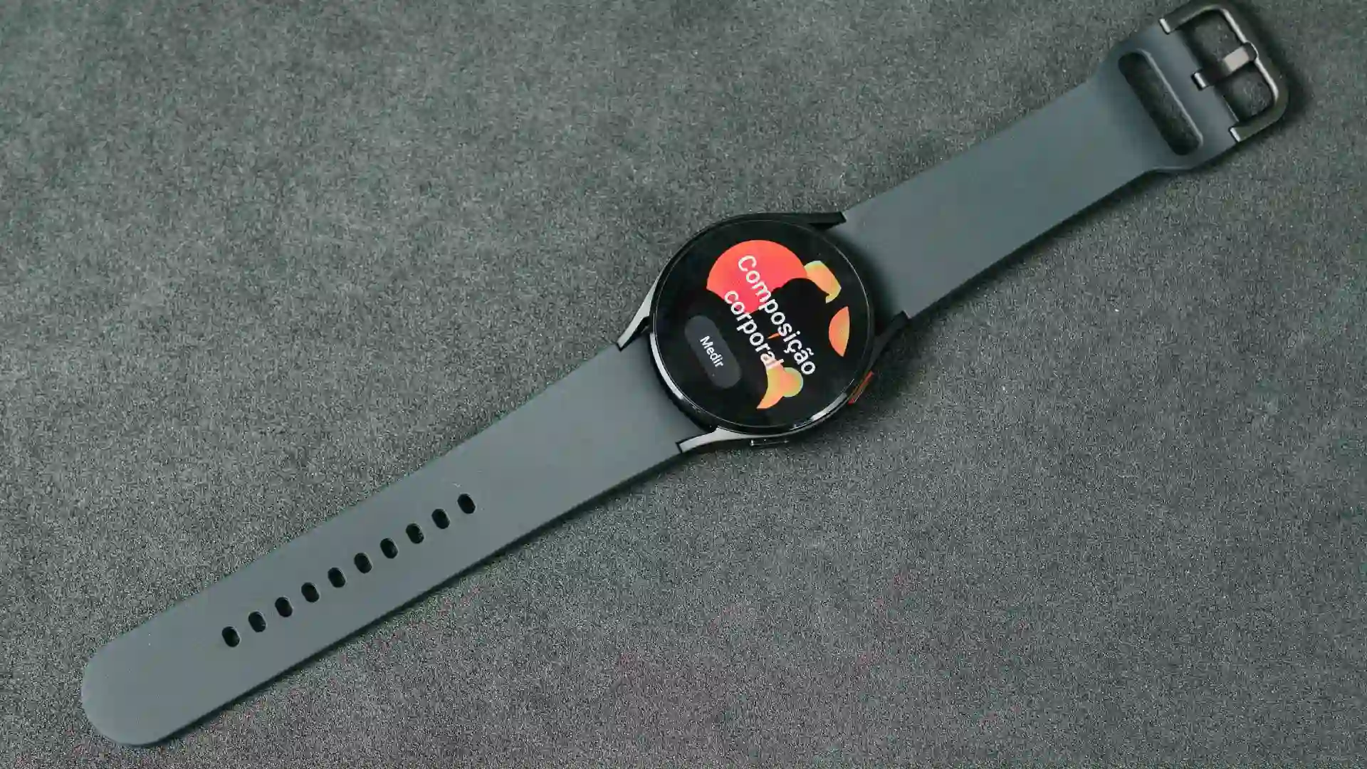 Foto de um Galaxy Watch 4 com o visor para cima e os dizeres "composição corporal"