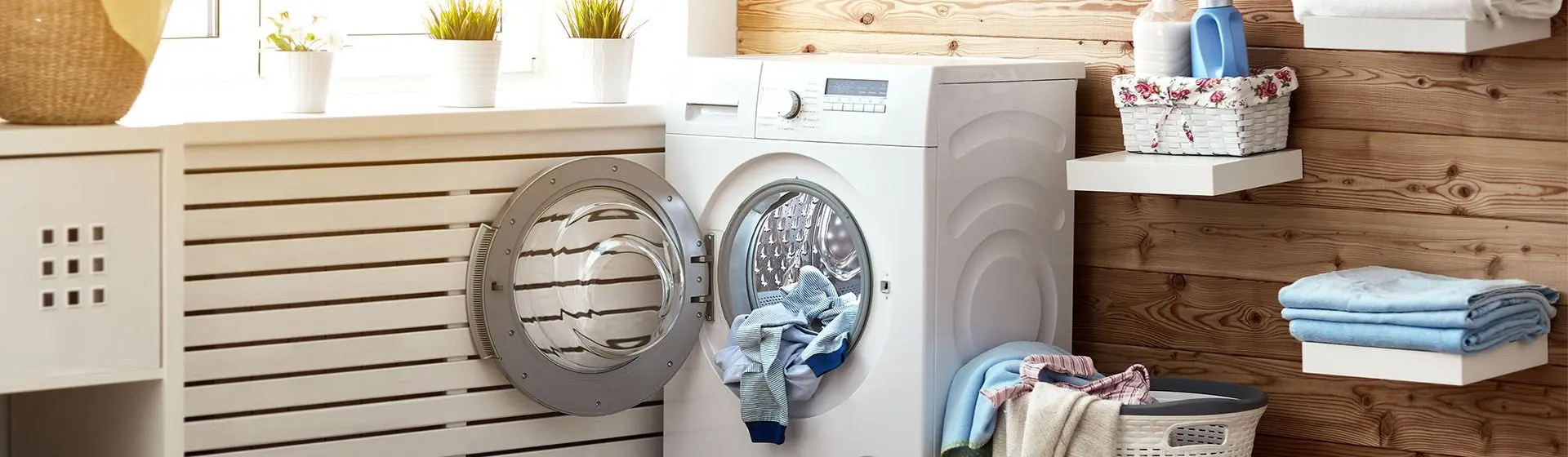 Lava e seca em uma lavanderia, com a porta aberta e roupas dentro, cercada de decorações