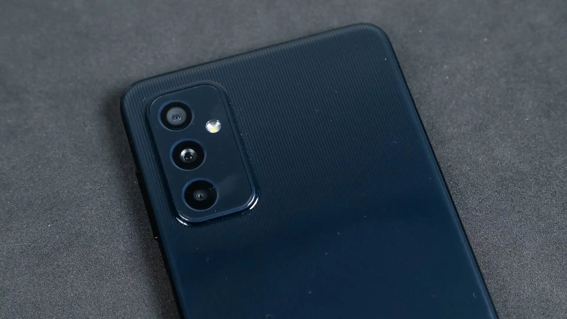 Três câmeras do Galaxy M52 na cor azul em destaque em fundo cinza
