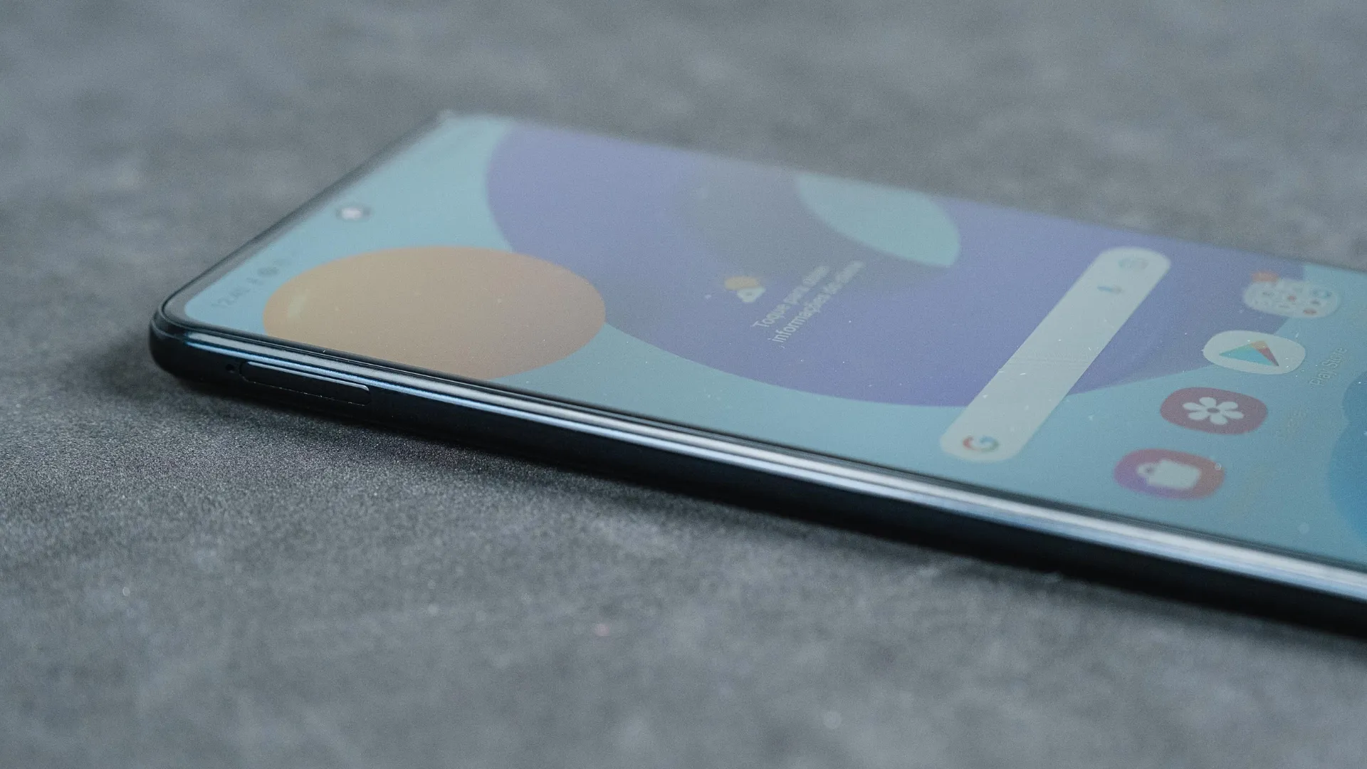 Celular Galaxy M52 de lado com a tela para cima em superfície cinza