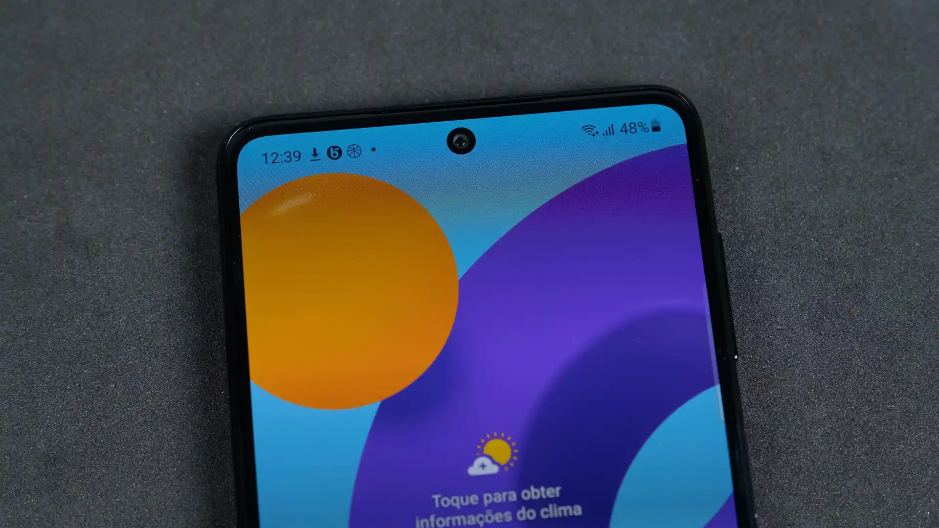 Tela do celular Samsung M52 em destaque deitado em fundo cinza
