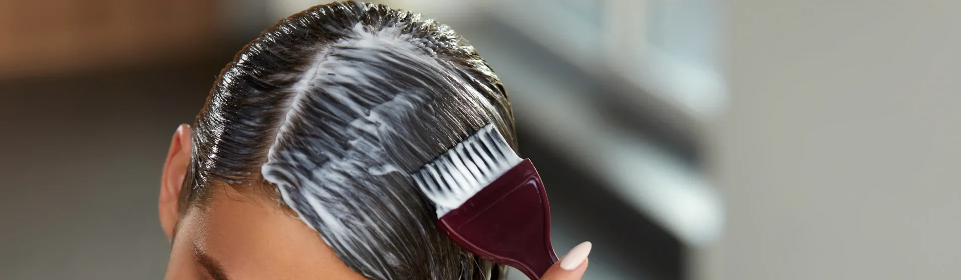 Mulher aplica um creme de tratamento no cabelo com um pincel