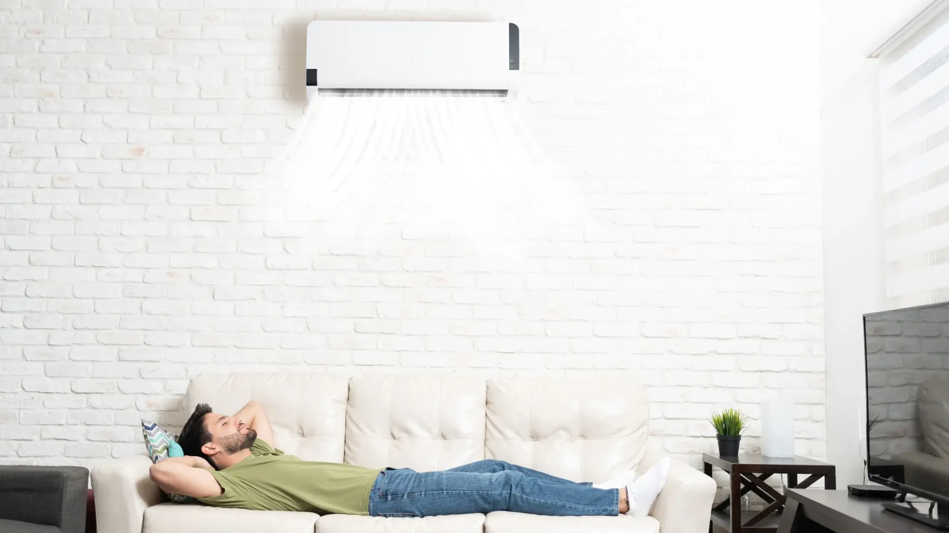 Ar-condicionado split instalado na parede e homem dormindo no sofá