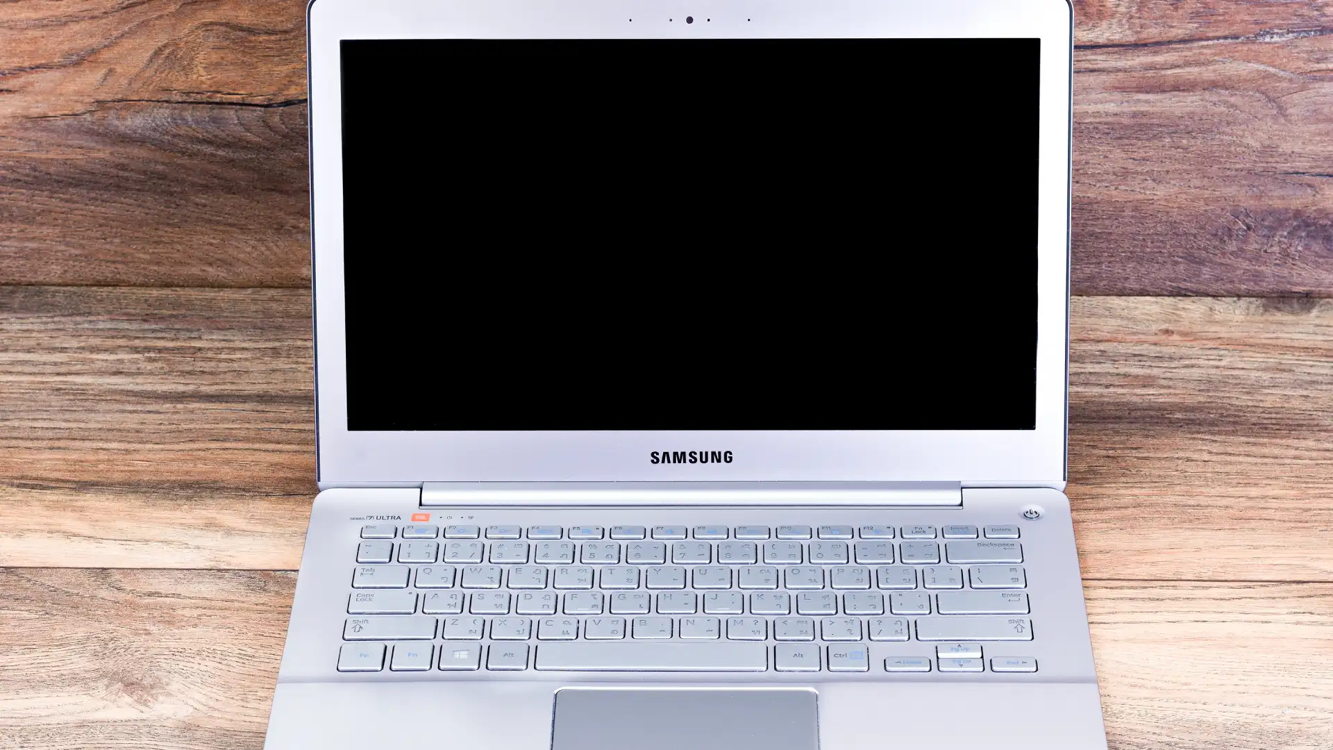 Um notebook Samsung branco aberto sobre uma superfície de madeira