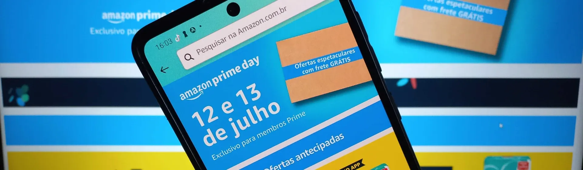 Foto de um celular na frente da tela de um notebook mostrando o app da Amazon 