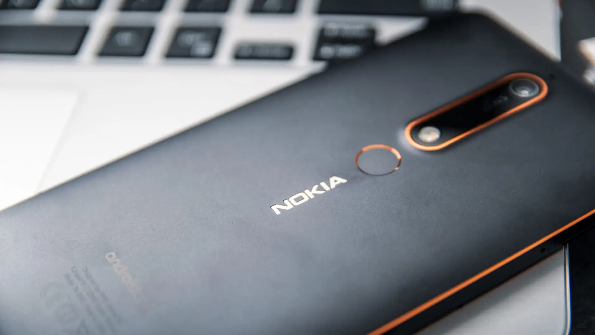 Modelo de celular da marca Nokia na cor preta apoiado em um teclado de notebook