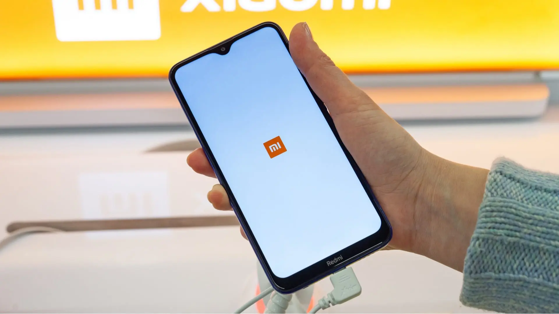 Mão segurando um aparelho da marca de celular Xiaomi, com a logo Mi na tela
