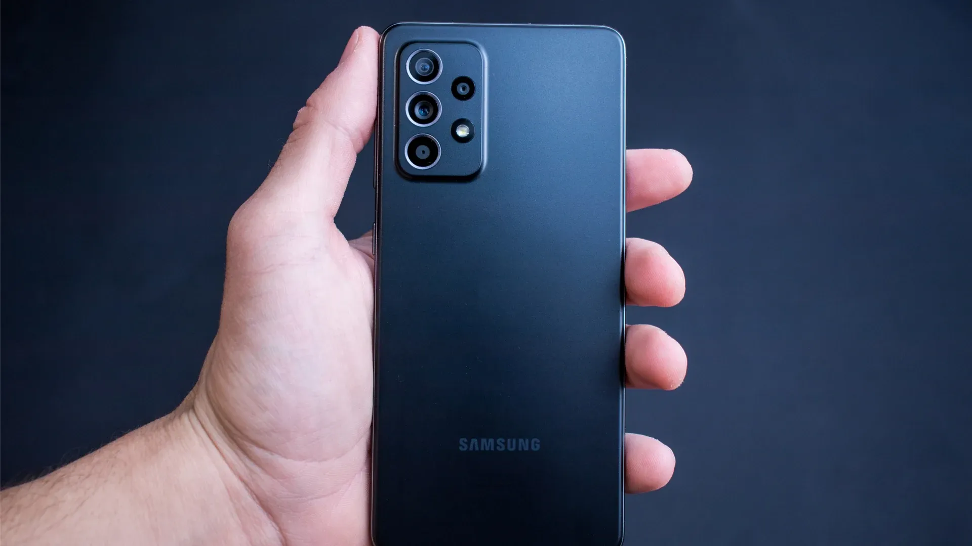 Celular Galaxy A52s preto na mão de homem em fundo preto